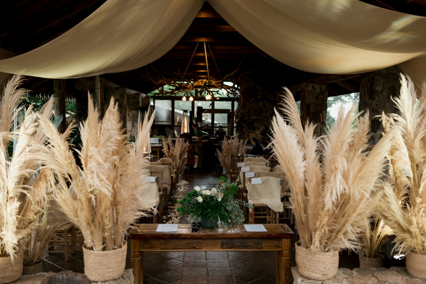 Large pampas grass arrangements in urns beside a wooden table