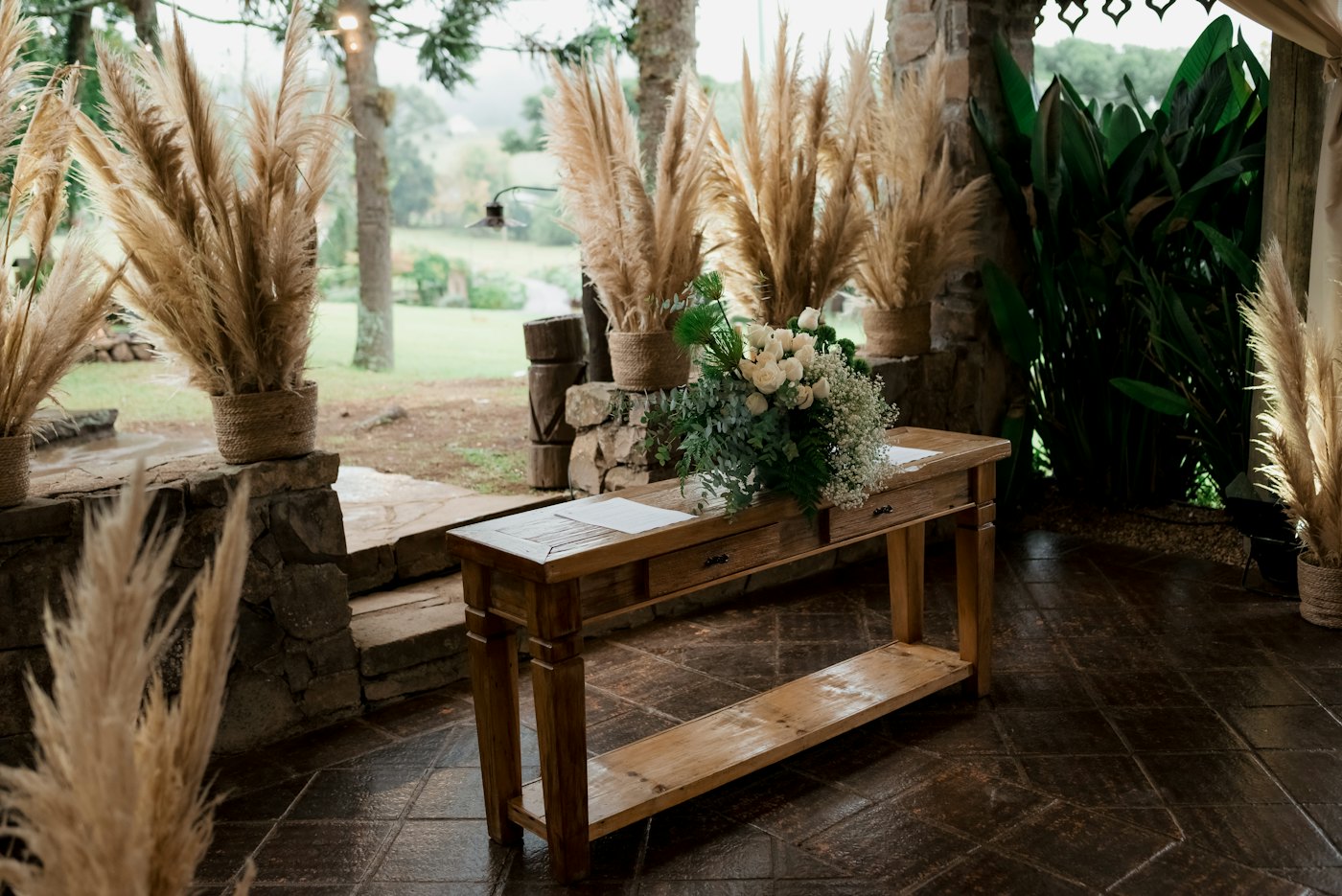 Wooden welcome table flanked by pampas grass